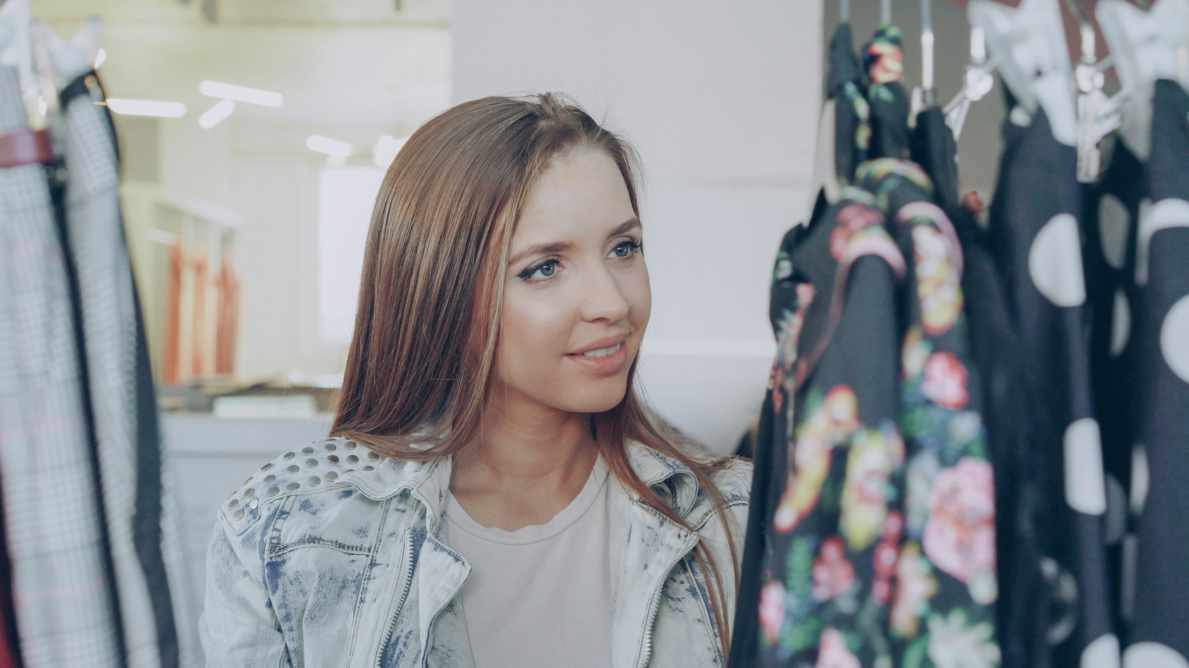 A shopper browsing colorful floral dresses on a clothing rack in a bright boutique
